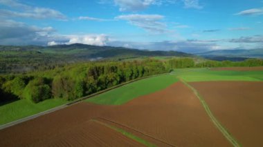 Bereketli ormanlar, tarım arazileri ve küçük köyleri olan güzel bir tepe manzarası. Tarımsal alanları ve vahşi ormanlık arazisi olan görkemli bir kırsal. Güneşli bir bahar gününde kırsal manzaralı Paved yolu.