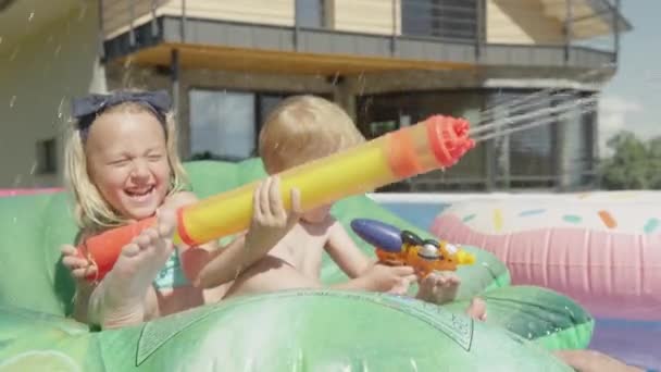 在游泳池派对上笑着让孩子们开心 同时用喷水器泼水 为炎炎夏日的水上运动添砖加瓦 孩子们在家里的花园里嬉笑着 享受着泼洒的水 — 图库视频影像