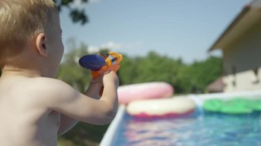 Küçük çocuğun babasıyla su savaşında eğlenirken çekilmiş dikiz görüntüsü. Havuzda bir çocuk ve ebeveyn arasında eğlenceli bir tatil anı. Sıcak yaz günleri için eğlenceli ve ferahlatıcı açık hava aktiviteleri.