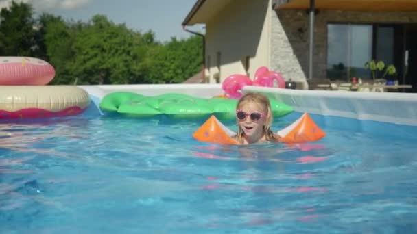 Close Χαριτωμένο Κοριτσάκι Γυαλιά Ηλίου Κολύμπι Στην Πισίνα Πλωτήρες Βραχίονα — Αρχείο Βίντεο