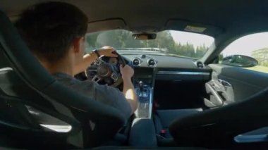 GIAU PASS, DOLOMITES, İTALYA, MAYIS 2022: virajlı asfalt dağ yolunda araba süren genç bir adamın arka koltuk görüntüsü. Güzel dağlık dağların yanından geçerken yılan kıvrımlarının üstesinden geliyorum..