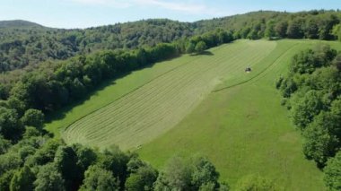 Yeşil çayırı biçmek için mekanik traktör çim biçme makinesi kullanan bir tarım işçisi. Tarım arazisi yetiştirmek için modern tarım makineleri. Resimli kırsal kesimde kırsal tarım manzarası.