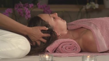 Genç bir bayan, güzellik salonunda kafa masajı yaptırıyor ve rahatlıyor. Profesyonel bir masöz tarafından nazikçe masaj yapılan bir kadın. Stres giderici spa tedavisi, vücut uyumu ve canlılık.