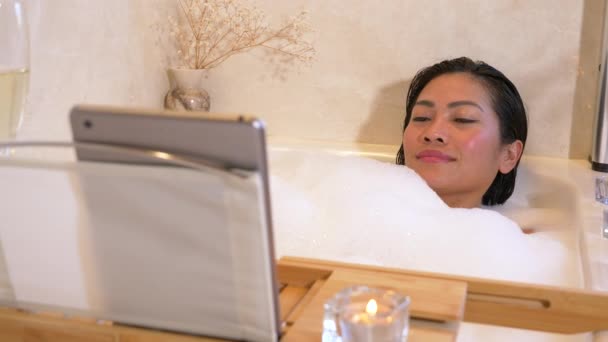 美丽的菲律宾女人一边在浴缸里放松 一边看喜剧 年轻的女士喜欢泡泡泡浴 电影娱乐和温泉疗养在一天结束后的放松时间 — 图库视频影像
