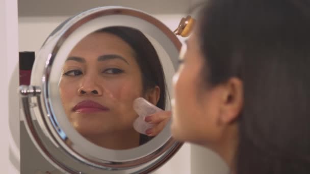 Підказка Вродлива Філіппінська Жінка Користується Нефритовим Скребком Самомасажу Обличчя Дзеркальне — стокове відео