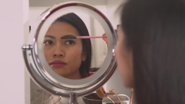 年轻女性用镜像画笔矫正眉毛形状 漂亮的菲律宾女士用眉毛装饰和塑造她的眉毛 女性完美的脸蛋化妆 — 图库视频影像