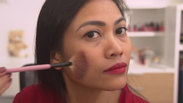 漂亮的亚洲女人用青铜粉做妆容 高兴的年轻女士完成了她的化妆后很高兴 在她的面颊上涂满了皱纹的女性 — 图库视频影像