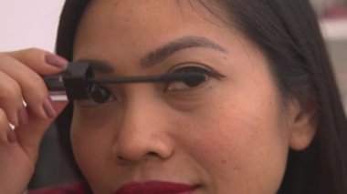 Filipinli güzel bir kadının kirpiklerine rimel sürerken detaylı görüntüsü. Özel bir durum için göz makyajı yapan genç bayanın vesikalığı. Bir kadın cazibeli görünüşüyle ilgileniyor..