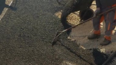 Nisan 2022, LJUBLJANA, SLOVENIA: Isıtılmış asfalt döşeyen ve yüzeyi düzleştiren bir grup inşaat işçisi. Erkekler sabah ışığında iş başında. Asfalt üniformalı adamlar garaj yolunu asfaltlıyor..