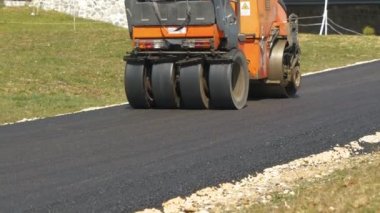 Yeni döşenmiş yol yüzeyini asfalt rulo makinesiyle sıkıştırıp düzleştiriyor. İnşaat makinelerini çalıştırırken güzel bir sabah ışığında eğimli garaj yolunu asfaltlamayı bitirmek..
