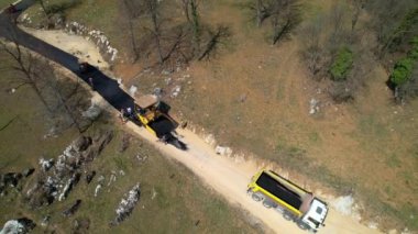 Yol işçileri inşaat alanında yeni asfalt döşeyerek yol açıyorlar. İnşaatçılar sabah vakti garaj yolunu asfaltlamaya hazırlanıyorlar. Yolu döşeyen inşaat işçileri.