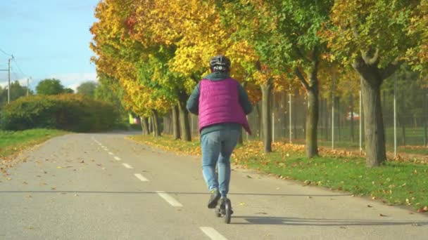 在秋天的一天 老太太开始开电动车的后视镜 老太太使用现代环保的通勤方式 美丽的秋日 乘坐电单车环城 — 图库视频影像