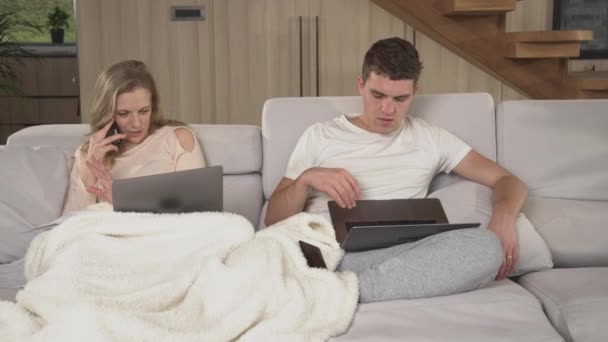 閉め出す隔離中に自宅で働いている若い夫婦が忙しいです 自宅から仕事をしようとしているパートナー間の迷惑の優しい覚醒 家庭で現代的なワイヤレスデバイスを使用している2人の大人 — ストック動画