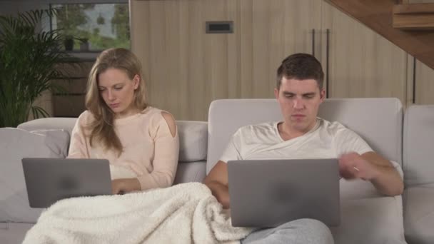 隔离中的学生夫妇试图履行他们的学习职责 这对年轻夫妇坐在铺着毯子的沙发上 孤身一人地使用笔记本电脑履行学业义务 — 图库视频影像