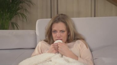 Korku filmi izlerken battaniyenin arkasına saklanan güzel genç bir kadın. Rahat bir koltukta oturan ve televizyon izleyen bir kadın. Kış akşamları için dinlenme etkinliği yapan kadın..