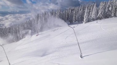 Kar makineleri kış kayak merkezinde yapay kar üssü hazırlıyor. Taze kar yağışından sonra güzel bir dağ kayak merkezi manzarası. Kış masalı kayak ve snowboard için hazır..