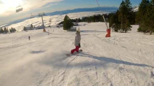 美しい景色を望むスキー場のスキー場を滑り降りる若い女性 アルペンスキーリゾートでのスキーやスノーボードのための冬のおとぎ話 冬のスポーツ活動で楽しむ女性スノーボーダー — ストック動画