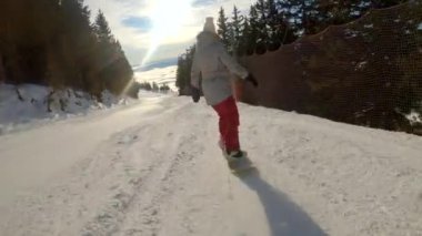 Güneşli bir kış gününde dağlarda snowboard yapan bir kadın. Kar kayağı ve kayak için mükemmel koşullar. Sisli vadinin üzerindeki muhteşem manzaralı dağlık kayak merkezinde..
