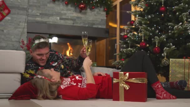 亲密接触 一对浪漫的年轻夫妇在圣诞节前夕在家里用香槟祝酒 美丽的一对恋人在壁炉前和圣诞树旁共度浪漫的夜晚 — 图库视频影像