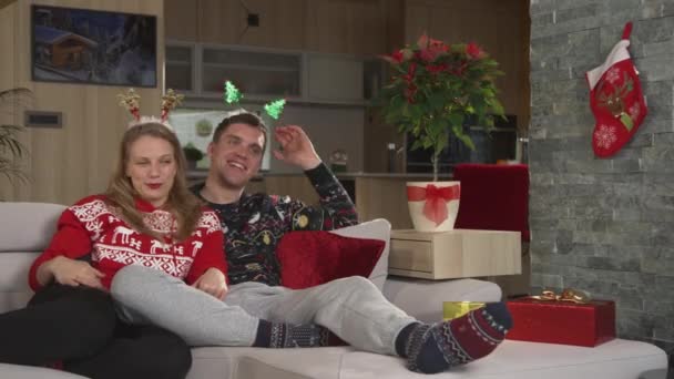 Laughing Young Couple Sitting Comfy Couch Watching Christmas Comedy Man — Vídeos de Stock