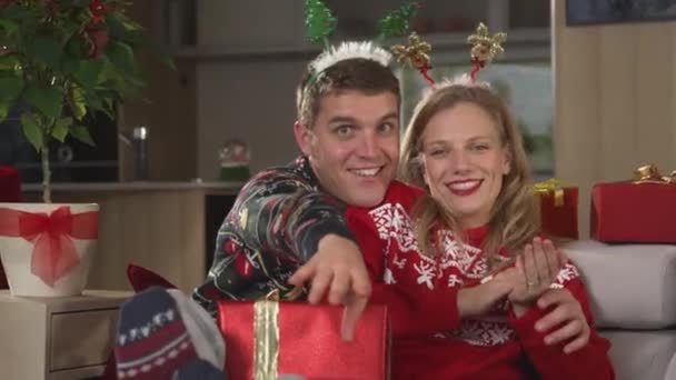 两人在沙发上悠闲地唱歌跳舞 享受节日气氛 穿着圣诞毛衣的一对快乐的夫妇在舒适的沙发上欢度佳节 享受轻松的节日时光 — 图库视频影像