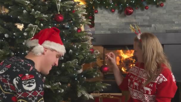 Cute Couple Festive Outfit Decorating Christmas Tree Burning Fireplace Young — Stockvideo