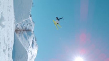 VOGEL, BOHINJ, JULIAN ALPS, SLOVENIA, MARCH 2022: SLOW MOTION: Young male freestyle skier jumping big air kicker at snowy snow park. Extreme athlete rotating through the air and performing grab trick.