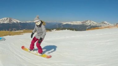 SLOW MOTION: Girl snowboarder falls in snow after losing balance while sliding the rail. Young female snowboarder tries to learn how to grind a rail in freestyle snow park at snowy mountain ski resort