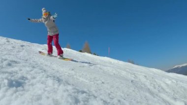 CLOSE UP: Young woman is learning to ride snowboard when she drops down on snow. Female beginner snowboarder crashes towards camera while making snowboard turn on slope at snowy mountain ski resort.