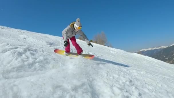 スローモーション 女性は雪の多いスキー場でスノーボードをしながら柔らかい雪に衝突します 若い女性スノーボーダーは美しい晴れた日にマウンテンスキーリゾートでスノーボードをオンにし 乗る方法を学ぶしようとします — ストック動画
