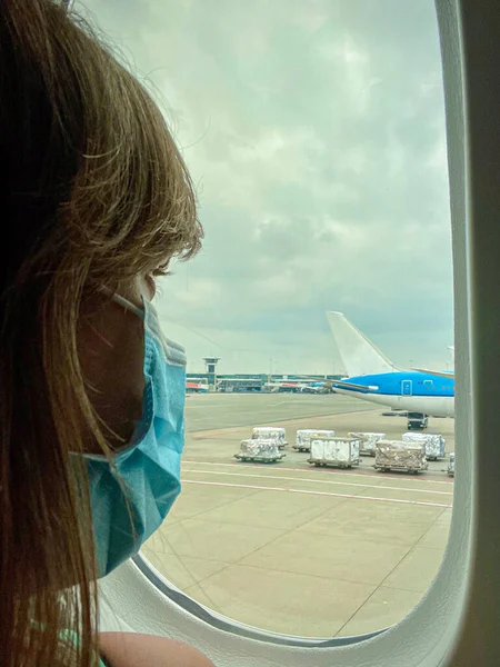 Young Caucasian Woman Wears Facemask While Looking Out Plane Window — Stockfoto