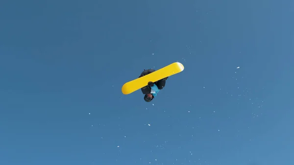 Spectacular shot of a young male snowboarder jumping off a kicker and doing an extreme spinning trick. Athletic male tourist snowboarding in the Slovenian Alps jumps into air and performs a spin trick