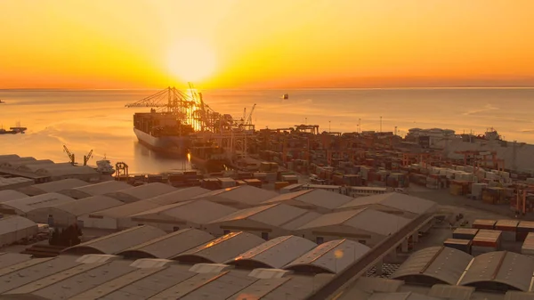 レンズフレア 大きな港の貨物ターミナルを照らす黄金の夜の日差しの絵のようなショット 息をのむような夕日がクレーンや貨物船に輝きます港に向かって航海 — ストック写真