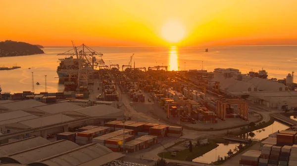 美しい晴れた夏の夜にKoperの港のドローンビュー ヨーロッパの大きな港の貨物ターミナルには黄金の朝の日差しが輝きます 港の倉庫の上に太陽が昇る — ストック写真