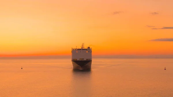 大型貨物船は豪華な黄金の夕日で重い貨物を輸送しています 日没時に商品を輸送する貨物船の壮大なドローンショット 産業用船舶の近くを飛ぶ — ストック写真