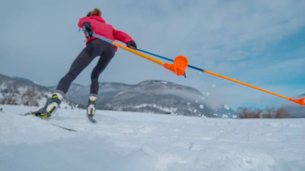 CLOSE UP, LOW ANGLE, DOF: Young woman prepares for the Olympic trials in Nordic skiing. Cinematic shot of unrecognizable female athlete during intense nordic ski training in the Slovenian mountains.