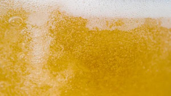 Macro Dof パブのタップから注ぐと 空のガラスの周りに泡立つビールが飛び散っています さわやかな金色の淡いエールは大きな瓶に注ぎ込まれます 上に上がる白い気泡 — ストック写真