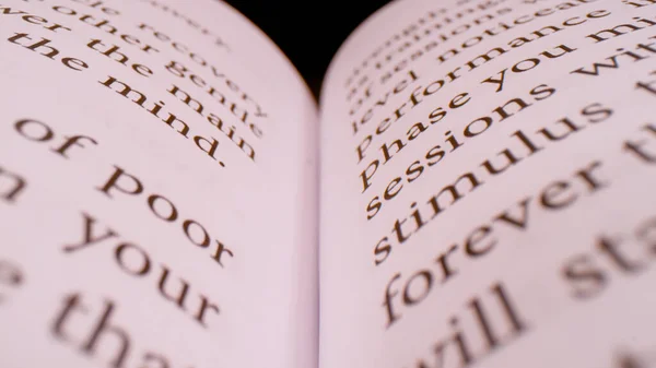 CLOSE UP, BOKEH: Detailed view of printed page text in an open book. Words and paragraphs of the open handbook in shallow focus. book sheet details with written content forming pattern.