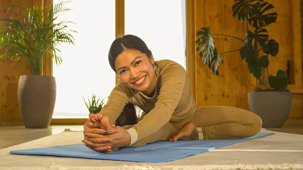 Asian Woman Smiling While Performing Seated Forward Fold Yoga Posture — стоковое фото