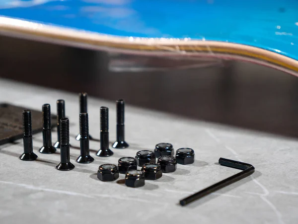 LA, UNITED STATES, APRIL 2022: CLOSE UP: Detailed high angle overview of arranged skateboard assembling parts. Ordered sequence of individual skateboard parts and tool on countertop ready for assembly