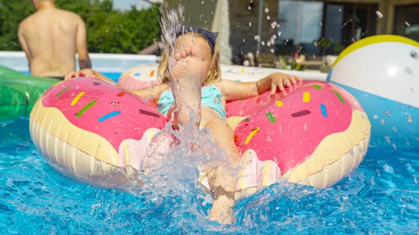 Sluiten Baby Girl Benen Spetterend Water Van Een Drijvende Donut — Stockfoto