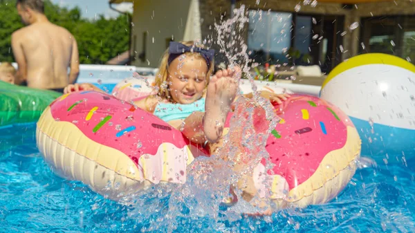 Egy Kislány Vizet Fröcsköl Miközben Úszó Fánkon Úszkál Medencében Aranyos — Stock Fotó