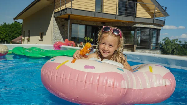 Close Adorable Girl Lying Floatie Pointing Water Gun Camera Cheerful — Stok fotoğraf
