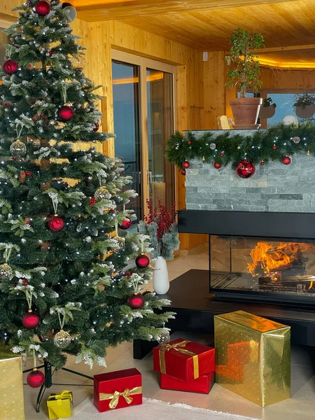 暖炉のそばに包まれたプレゼントと美しく装飾されたクリスマスツリー クリスマスの前夜を祝うための牧歌的な家庭環境 金の色で素敵な伝統的なお祝いの装飾 — ストック写真