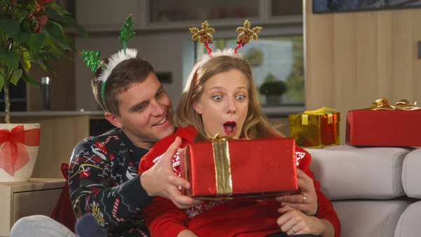 Веселый Мужчина Удивляет Свою Девушку Подарком Рождество Прекрасная Пара Сидит — стоковое фото