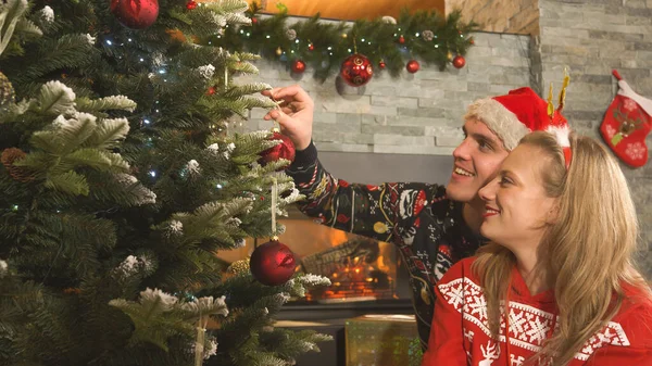 Handsome Man Hangs Bauble Christmas Tree Company His Beautiful Lady — Stockfoto