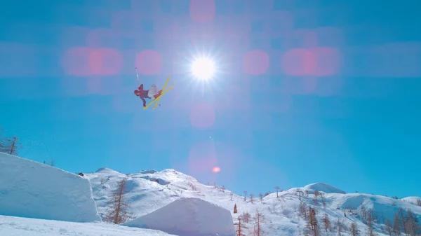 Extreme freestyle skier flying through air after jumping big air. Young male athlete in action at snow park in ski resort. Winter adrenaline action in snow-covered alpine mountains.