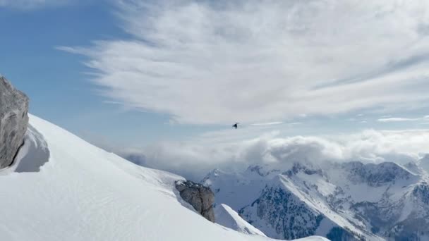 低い角度ビュー ヘリスキングヘリコプターは絵のように美しい雪の山の上を飛んでいます 息をのむような素晴らしいアルバニアの手付かずの山々での冒険的なフリーライドヘリオボーディングのためのフライト輸送 — ストック動画