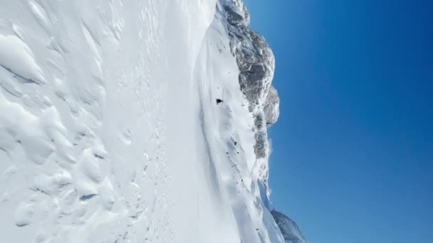 低い角度ビュー スノーボーダーやスキーヤーを落とした後のヘリコプターのフライオーバー 雪に覆われたアルバニアアルプスで 手付かずの自然のままの地形でヘリコプターやヘリコプターに乗るための息をのむような場所 — ストック動画