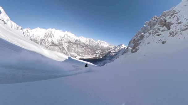 若い女性が山の斜面を滑りながら新雪を噴霧した後 絵のように新鮮な雪に覆われた山々を受け入れるパウダースノーを楽しむ女性スノーボードライダー — ストック動画